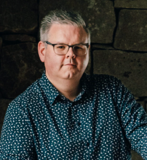 Ryan Molloy portrait photo in colour of him behind a piano